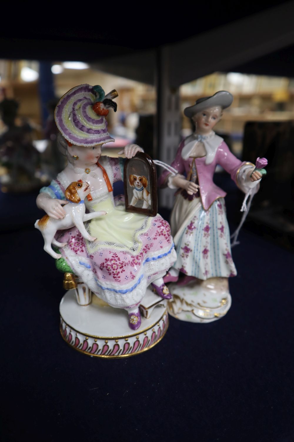 A late Meissen figure of a young girl with a spaniel and another of a young lady with a rose, 19th century, height 14.5cm (faults)